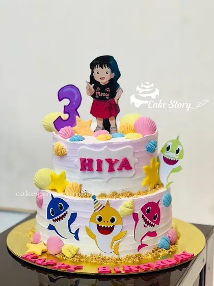 A fun Baby Shark themed cake for a 3rd birthday. This two-tier cake is decorated with the whole shark family, colorful shells, and an underwater feel.