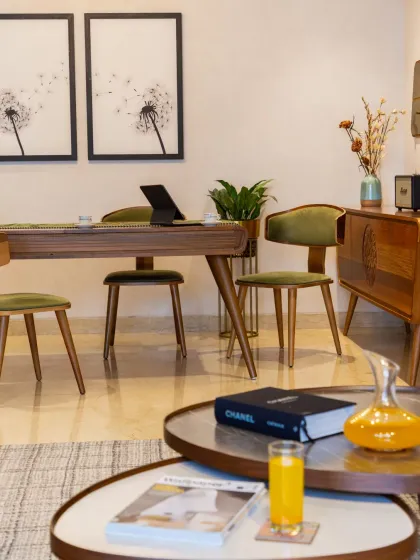 A detail from the dining area, where mid-century modern inspired chairs in olive green velvet are paired with delicate artwork, creating a space that feels both nostalgic and contemporary.