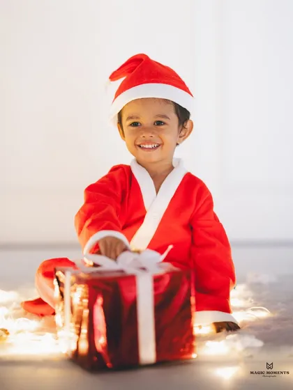 The magic of twinkling lights. This simple, beautiful portrait shows a boy in his Santa costume, surrounded by a warm glow, creating an image filled with holiday wonder.