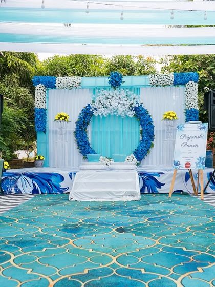 A unique Haldi setup with a blue and yellow color scheme. The stage features a large floral ring backdrop, creating a modern and refreshing look for the ceremony.