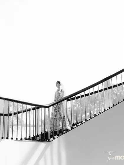 A minimalist black and white portrait. The bride's silhouette as she ascends a modern staircase creates a powerful, artistic image focused on lines, light, and form.