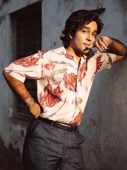Zahan Kapoor leaning against a rustic wall in the warm afternoon sun. The light brings out the rich colors of his shirt and the texture of the wall.