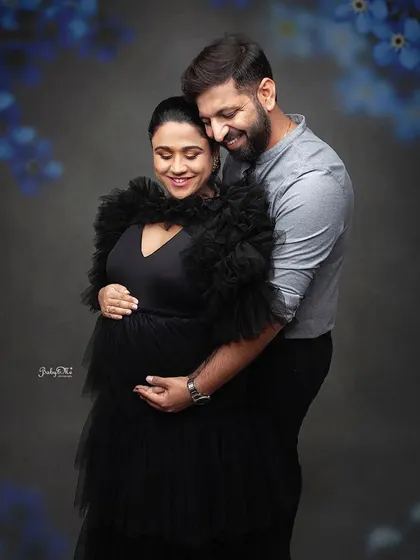 A tender moment captured between the parents to be. The soft lighting and dark background create a romantic atmosphere for this maternity photo.