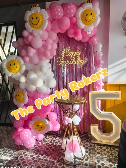 A sweet and happy flower and smiley-themed 5th birthday. The pink and white balloon arch is decorated with large smiley-face flower balloons, creating a cheerful atmosphere.