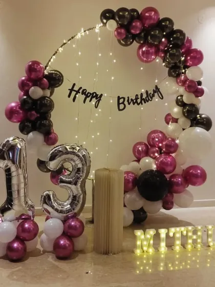 A beautiful ring decoration for a 13th birthday at home. The combination of chrome balloons, fairy lights, and number balloons makes for a trendy and memorable setup.