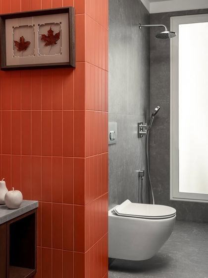 Welcome your guests to a splash of style. This guest bathroom combines bold terracotta orange tiles with sleek grey walls and modern fixtures, creating an inviting oasis with a touch of warmth and luxury.
