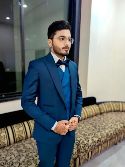 A side profile of the groom, showing the clean lines of his haircut and the subtle definition from the makeup. Even with henna on his hands, the overall look is modern and sharp.