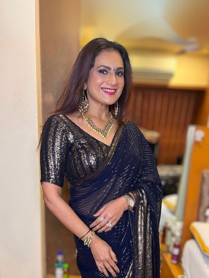 A glamorous look for a night out. This client is wearing a sparkling navy blue saree, and her makeup is equally stunning, with a bold lip and defined eyes.
