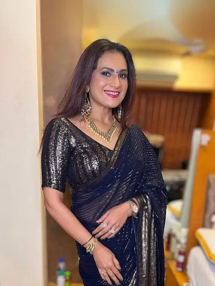 A glamorous look for a night out. This client is wearing a sparkling navy blue saree, and her makeup is equally stunning, with a bold lip and defined eyes.