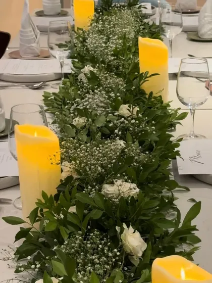 A closer look at the texture and detail within our greenery table runner. The combination of different leaves, delicate baby's breath, and soft white roses adds depth and sophistication to the tablescape.