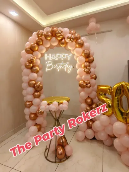 The complete 50th birthday home decoration, showing the balloon arch, neon sign, cake table, and foil numbers, all fitting neatly in the room.