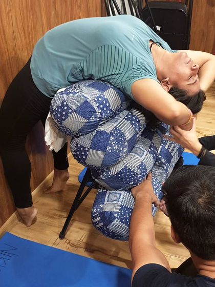 A student relaxes into a fully supported wheel pose. With the help of an instructor's hands and props, the body can surrender and find deep release in the backbend.