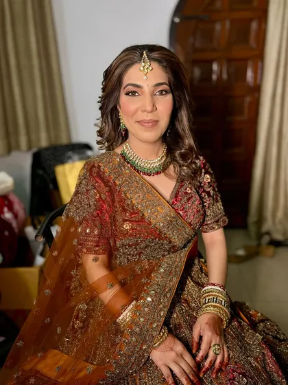 A full shot of the bride sitting, looking calm and beautiful before her ceremony. The rich colours of her lehenga are stunning.