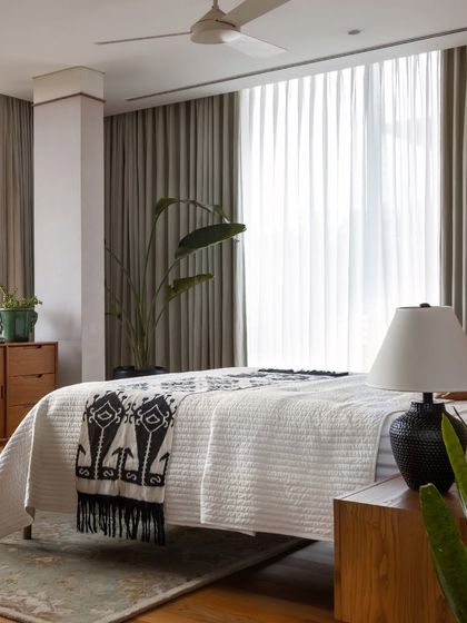 Natural light floods this bedroom through sheer curtains, creating a soft and serene atmosphere. The focus is on comfort and tranquility.