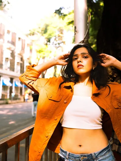 This shot captures a confident and direct gaze, using the bright sunlight and open street to create a fresh, energetic feel.
