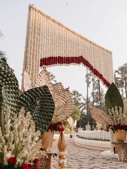 The entrance walkway, featuring floral arrangements with woven palm leaves and brass elements.