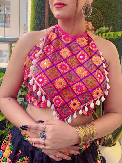 A close-up of a unique halter-neck blouse with Kutchi embroidery and shell tassels, a modern twist on traditional Garba wear.