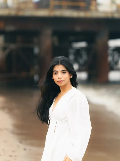 A classic portrait with the out-of-focus pier and sea in the background. The focus is entirely on the model's calm expression.