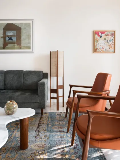 A view of the living room, showcasing the interplay between a modern sofa and classic leather armchairs. I design and select furniture to create a balanced and artful conversation between different styles and materials.