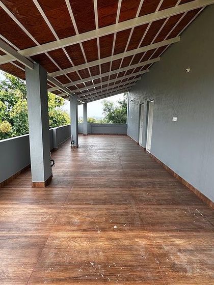 The finished result. A spacious balcony with wood-finish floor tiles and a sloped roof, ready for the client to enjoy. This shows the transformation from a construction site to a beautiful space.