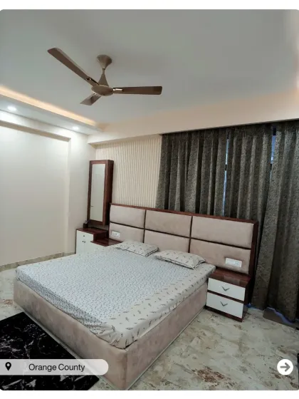A bedroom in Orange County with a clean design, featuring a two-toned headboard and a simple false ceiling with cove lighting.