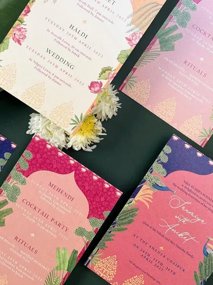 Another view of the colorful invitation suite, showcasing the cards for the Mehendi and Cocktail Party. The rich pinks and blues are balanced with beautiful botanical illustrations.