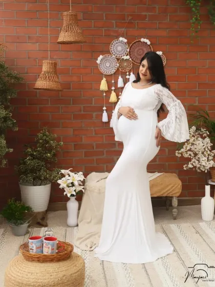 A full-length view of the elegant white gown in the cozy corner setup. The simplicity of the dress allows her natural glow to be the star.