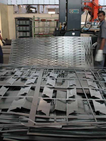In the factory, sheets of metal are cut to create the intricate 'jaalis' for the LMW Headquarters. The leftover scrap, seen in the foreground, highlights the process of transformation from industrial waste to architectural art.