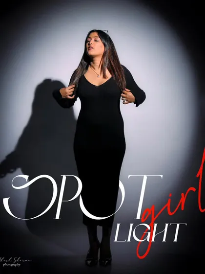 A spotlight on the model, creating a dramatic 'Spot Girl' magazine concept. The play of light and shadow emphasizes her presence and the simple elegance of the black dress.