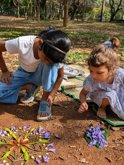 Two little artists collaborating on a beautiful flower mandala on the ground. This activity encourages teamwork and an appreciation for natural colors and patterns.