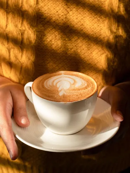 A simple, beautiful shot of a cappuccino, using natural sunlight and shadows to create a warm, cozy feeling. This kind of lifestyle photography helps cafes sell an experience, not just a coffee.