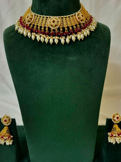 A simple choker set with red beads and pearl drops, paired with matching jhumkas. This is a great rental option for pre-wedding functions.