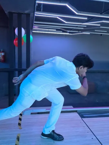 A player in a classic bowling pose, concentrating on their shot. The modern, linear lighting on the ceiling adds to the sleek design of our gaming arena.