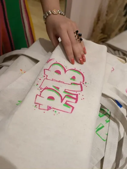 The finished product. This tote bag features a custom initial with a cool, layered 3D effect, all hand-painted live at the event. Guests love taking home a functional and personalized piece of art.