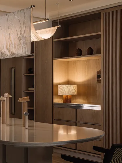 A moody shot of the Kanso House dining area on a rainy day. The soft lighting from the table lamp and the fabric fixture creates a cozy and intimate atmosphere.