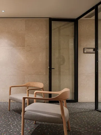 A seating detail on the mezzanine level at Elevate, showcasing the elegant wooden chairs and terrazzo flooring. The design focuses on clean lines and high-quality, tactile materials.
