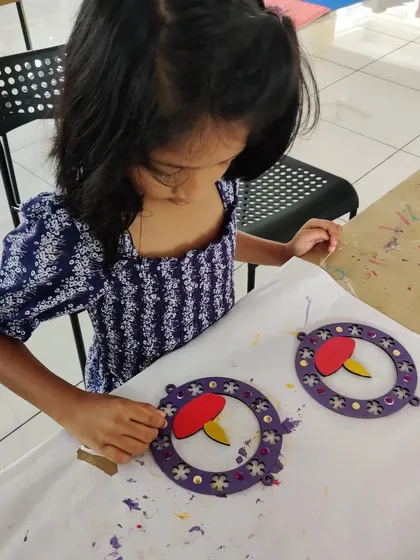 A young artist is focused on creating a decorative wall hanging with a diya design for Diwali.