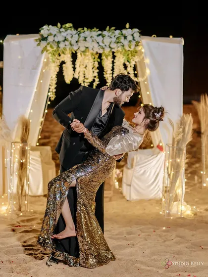 A magical evening on a Goa beach. The combination of a sequined gown, a classic tuxedo, and the soft glow of fairy lights creates an incredibly romantic and celebratory atmosphere for a pre-wedding dance.