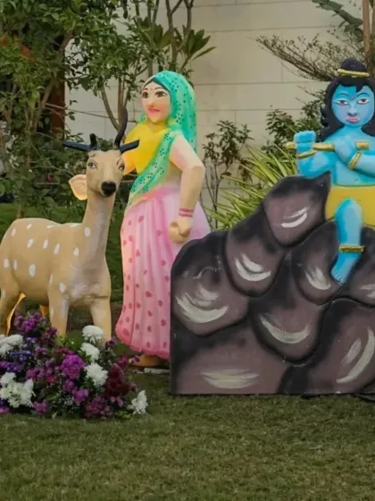 Life-sized props depicting Krishna and a gopi with a deer. These detailed cutouts add a narrative element to the decor, helping to bring the story of Vrindavan to life for guests.