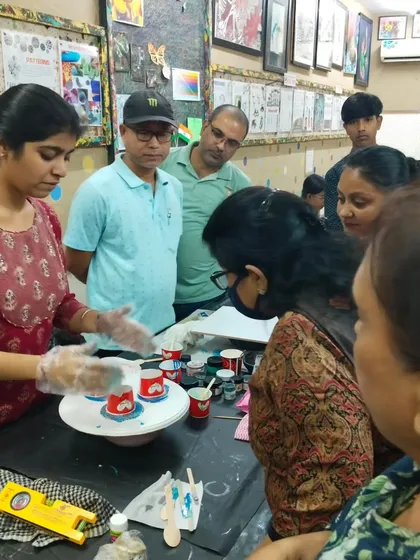 An instructor demonstrating the fluid art pouring technique to an engaged group of students during a hands-on resin class.