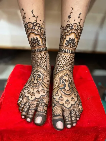 This elegant foot design features large peacock and jhumka (earring) motifs. The pattern extends up from the toes with delicate floral vines, leaving some skin visible for a lighter feel.