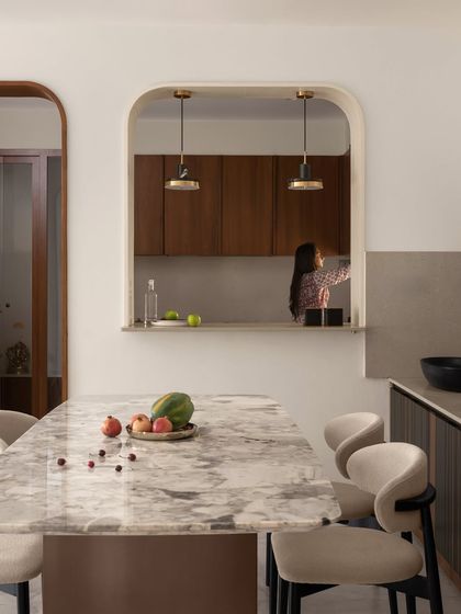 An arched pass-through window connects the kitchen and dining areas, making the home feel more social and open. This architectural feature adds a soft, organic curve to the space.