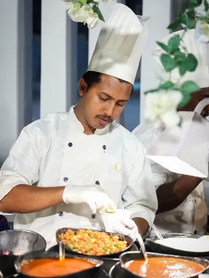 Another angle of our chef preparing a dish with fresh ingredients at a live counter. Our open kitchens allow guests to see the quality and care we put into our food.