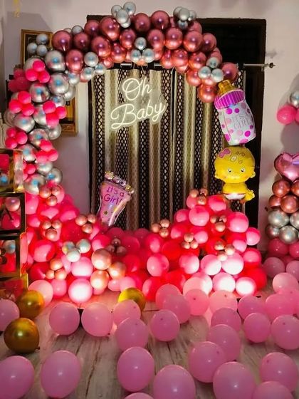 A vibrant "Oh Baby" setup for a baby girl, with a room filled with pink and rose gold balloons and "BABY" blocks.