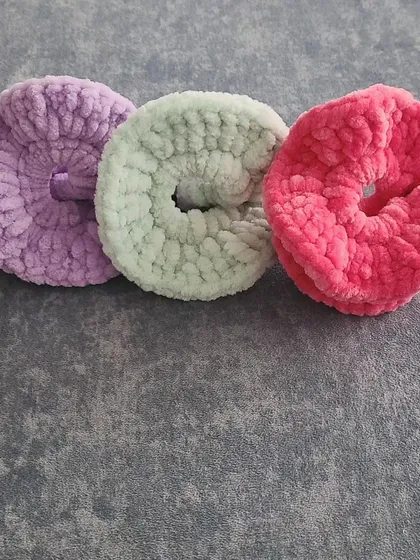 Here are three of my handmade crochet scrunchies lined up, showing their donut-like shape. The velvet yarn I use is incredibly soft to the touch and provides a comfortable, no-snag hold for your hair.