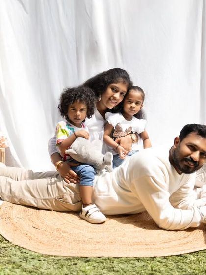 A playful family photo on a picnic blanket outdoors. The kids sit on their dad's back, creating a fun, candid moment full of laughter and love.