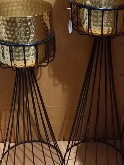 This is another design for tall metal planters. The gold hammered pot sits within a black wireframe stand that has a modern, geometric feel.