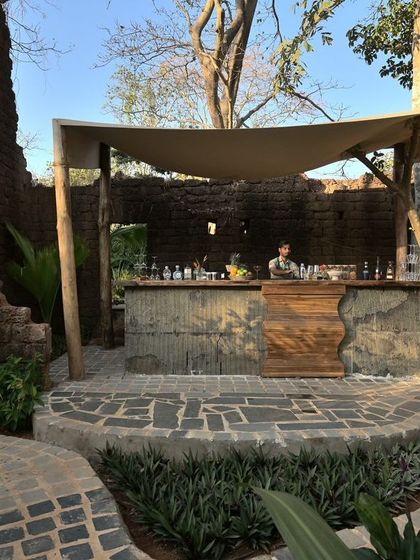 The bar at Sanctuary, nestled within the stone ruins and shaded by a simple canopy. The design is rustic yet refined, respecting the history of the site while creating a functional and inviting space.