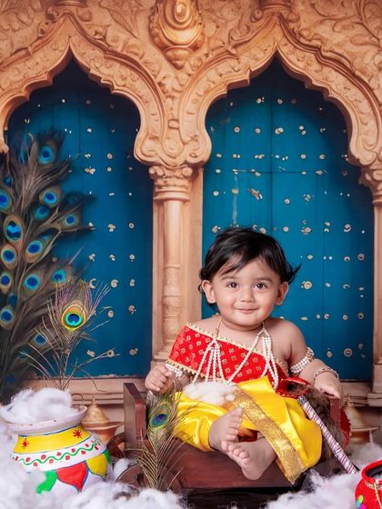 A sweet smile from our little Krishna, surrounded by peacock feathers and a pot of makhan.