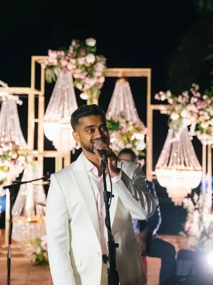 The groom serenades his bride at their cocktail party, with a stunning backdrop of cascading crystal chandeliers.